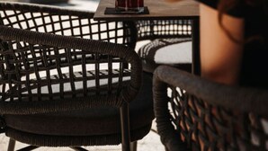 Una persona sentada en una cafetería al aire libre con una bebida delante.