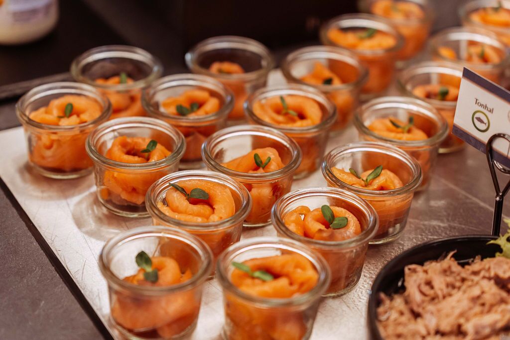 A buffet table with small glass containers of food, a sign indicating 'Tonhal', and a bowl of shredded meat.
