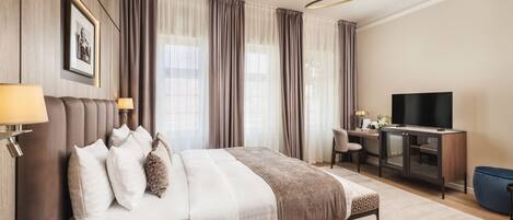 A hotel room with a large bed, a desk, a television, and a minibar.