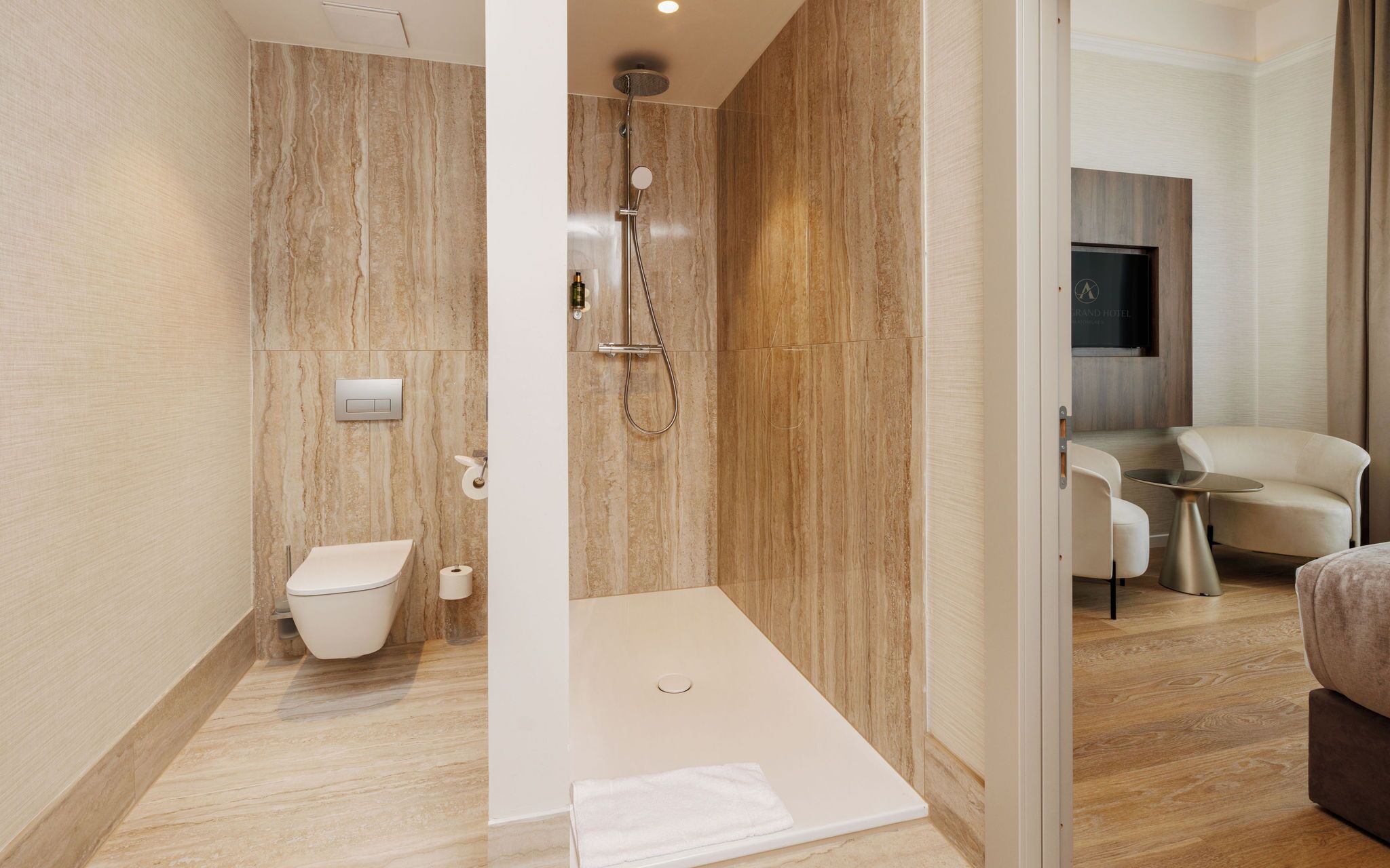 Ein modernes Badezimmer mit Dusche, Toilette und einer Sitzecke mit Tisch und Stühlen.