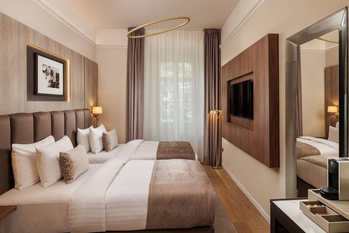 A hotel room with a large bed, a flat-screen TV mounted on the wall, and a mirror.