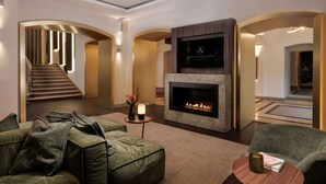 Un moderno vestíbulo de hotel con chimenea, asientos cómodos y una escalera.