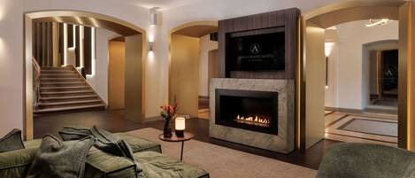 A modern hotel lobby with a fireplace, comfortable seating, and a staircase.