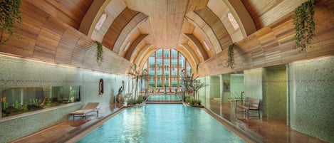 Una piscina techada, una piscina al aire libre, sombrillas