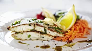A plate of food with fish, vegetables, and a lemon wedge.