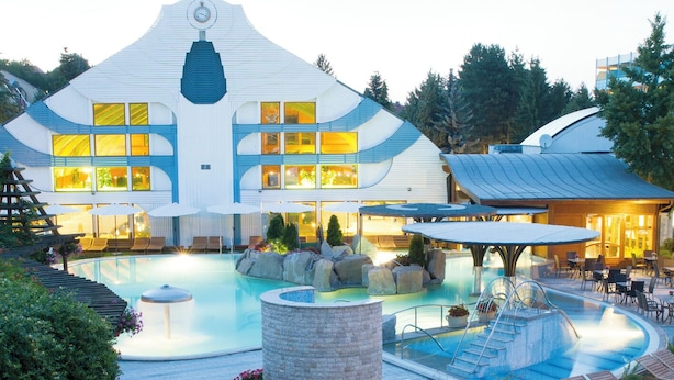 Ein Resort mit Swimmingpool, Liegebereichen und einem markanten Gebäude mit einer Uhr.