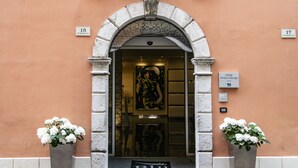 L’entrée de l’hôtel Antico Borgo se distingue par une arche en pierre, un paillasson bleu et deux plantes en pot.