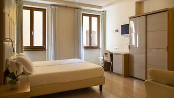 Une chambre d’hôtel avec un lit, un bureau, une télévision et une armoire.