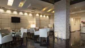 Un hall d’hôtel moderne avec une grande colonne en pierre, des fauteuils confortables, un téléviseur à écran plat et un sol propre et bien entretenu.