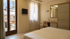 Une chambre d’hôtel comprenant un lit, un bureau, une chaise, une télévision, un balcon avec une chaise et une porte coulissante.