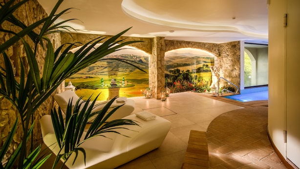 Interior luxuoso com um arco de pedra, um sofá branco e vista para uma paisagem através do arco.