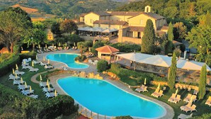 Um resort com uma piscina grande, espreguiçadeiras e vista para as colinas ao redor.