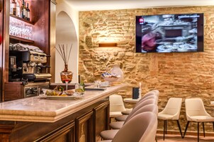 Un área de bar con pared de piedra, un televisor montado y taburetes de bar.