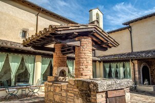 Un patio con un banco de piedra, una pérgola y una chimenea de ladrillo.