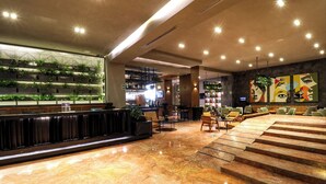 A modern lobby with a marble floor, a reception desk, a seating area, and a wall with vertical gardens and artwork. - St Isidro Suites Corporate Housing SPA & Wellness Center (Mexico City)
