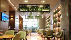 A restaurant with a long counter, green chairs, and a ceiling with hanging plants. - St Isidro Suites Corporate Housing SPA & Wellness Center (Mexico City)