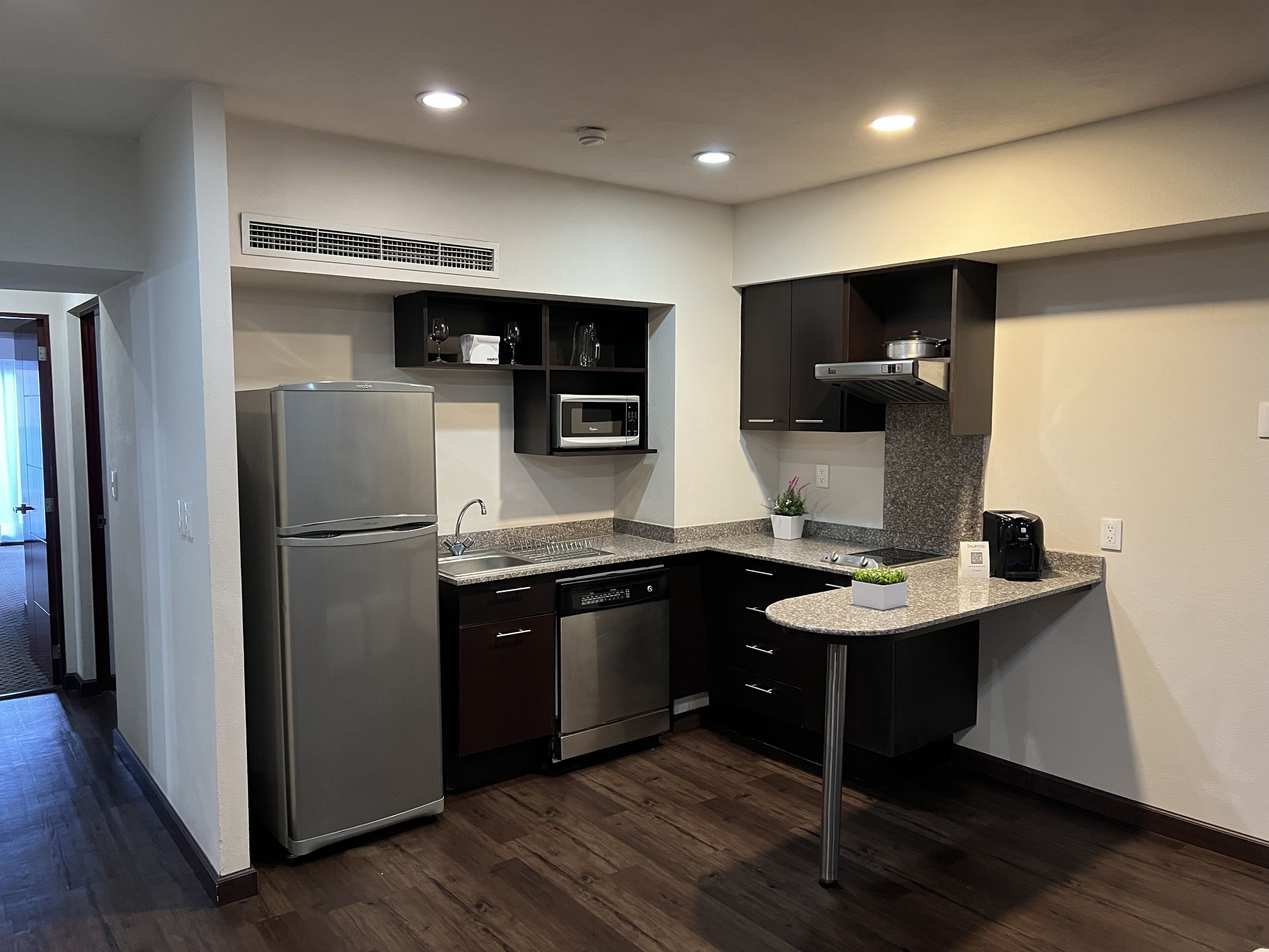 A modern kitchen with a stainless steel refrigerator, a microwave, a dishwasher, and a coffee maker.