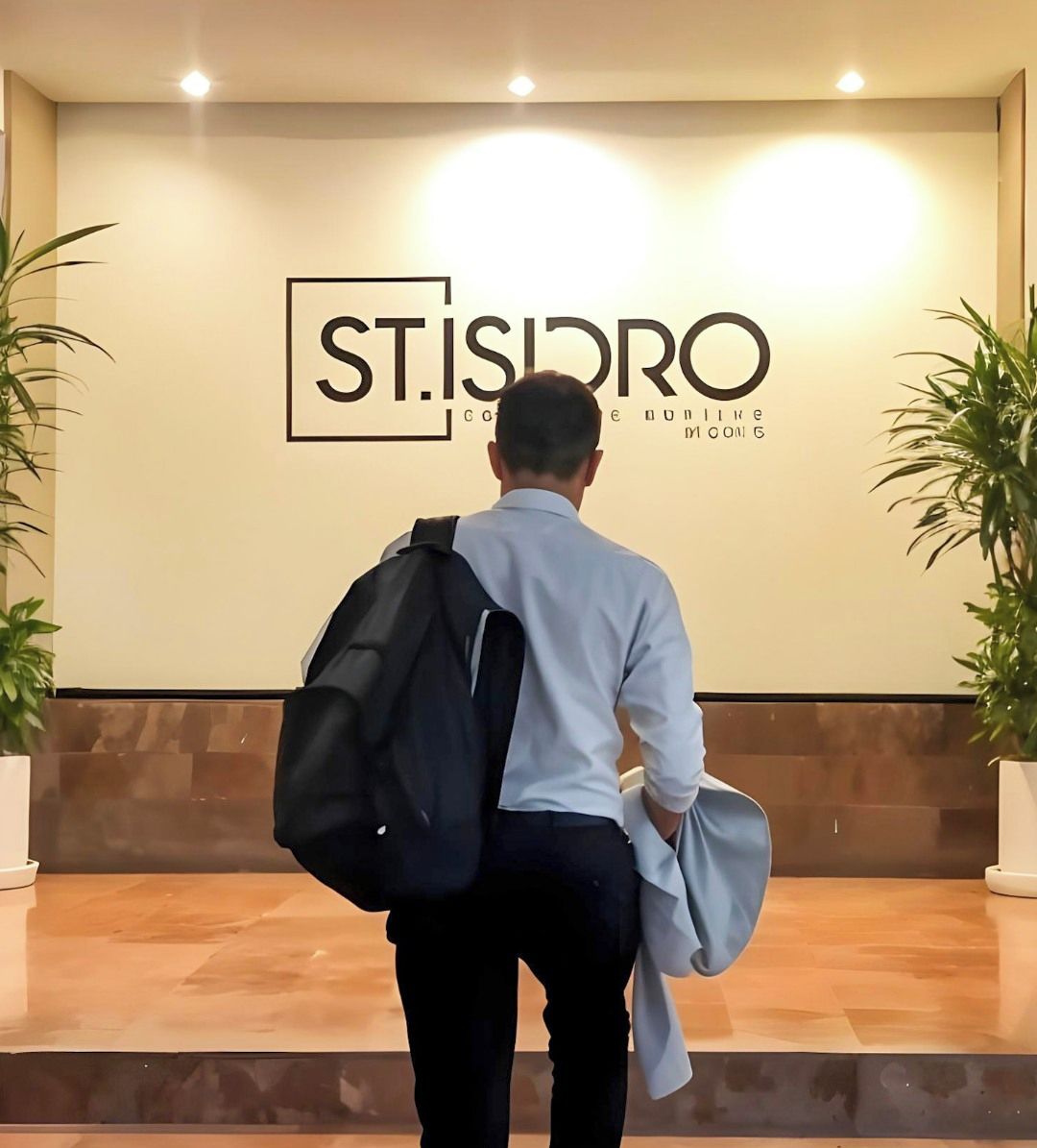 A man walking up a set of stairs towards a wall with the text "ST. ISIDRO" and "comune di Milano" visible.