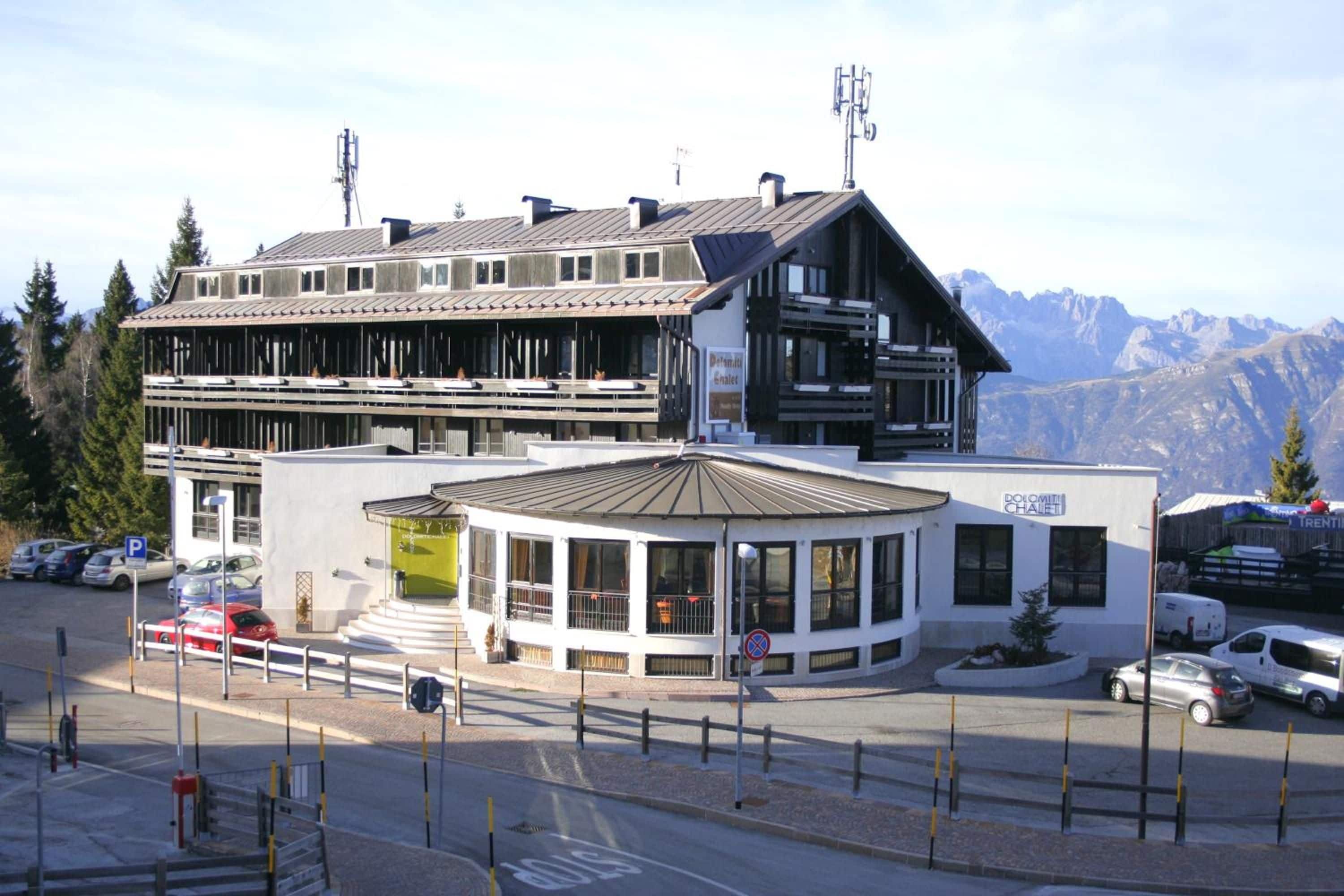 A hotel with a modern design, featuring a large glass entrance and a view of the mountains.