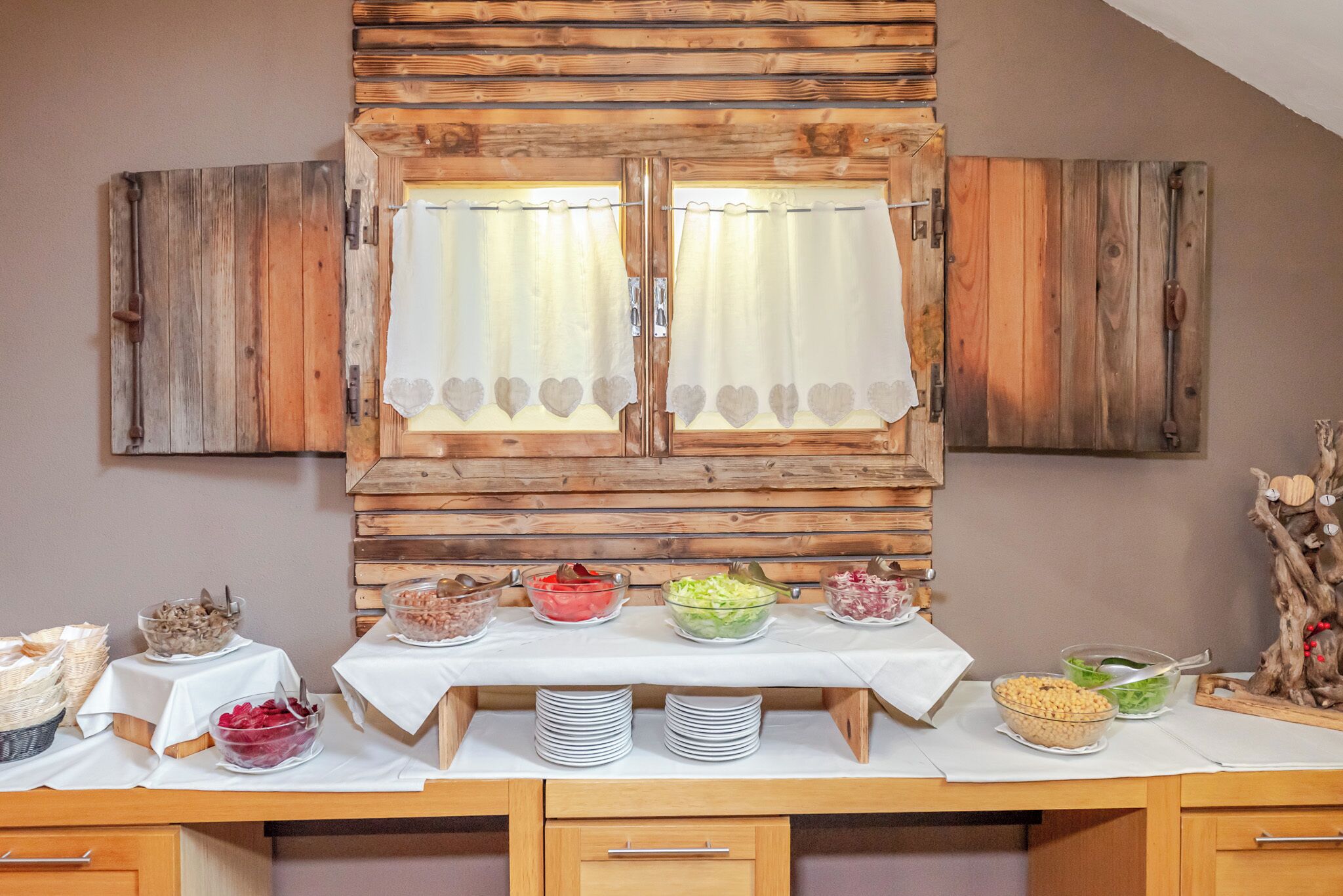 Un buffet avec différents plats disposés sur une table, des murs en bois et une fenêtre avec des rideaux.