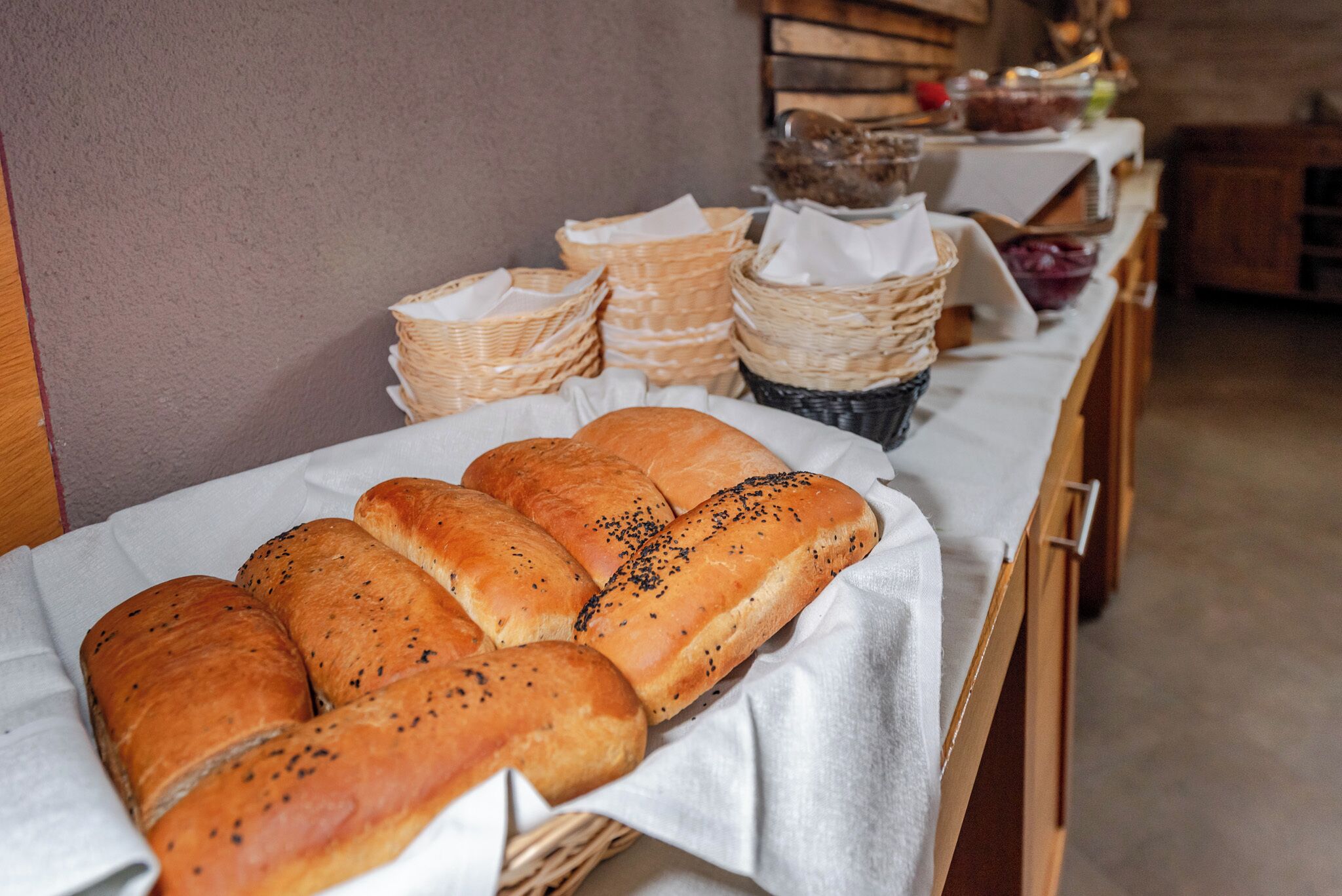 Ein Tisch mit Körben voller Brot und verschiedenen Beilagen.