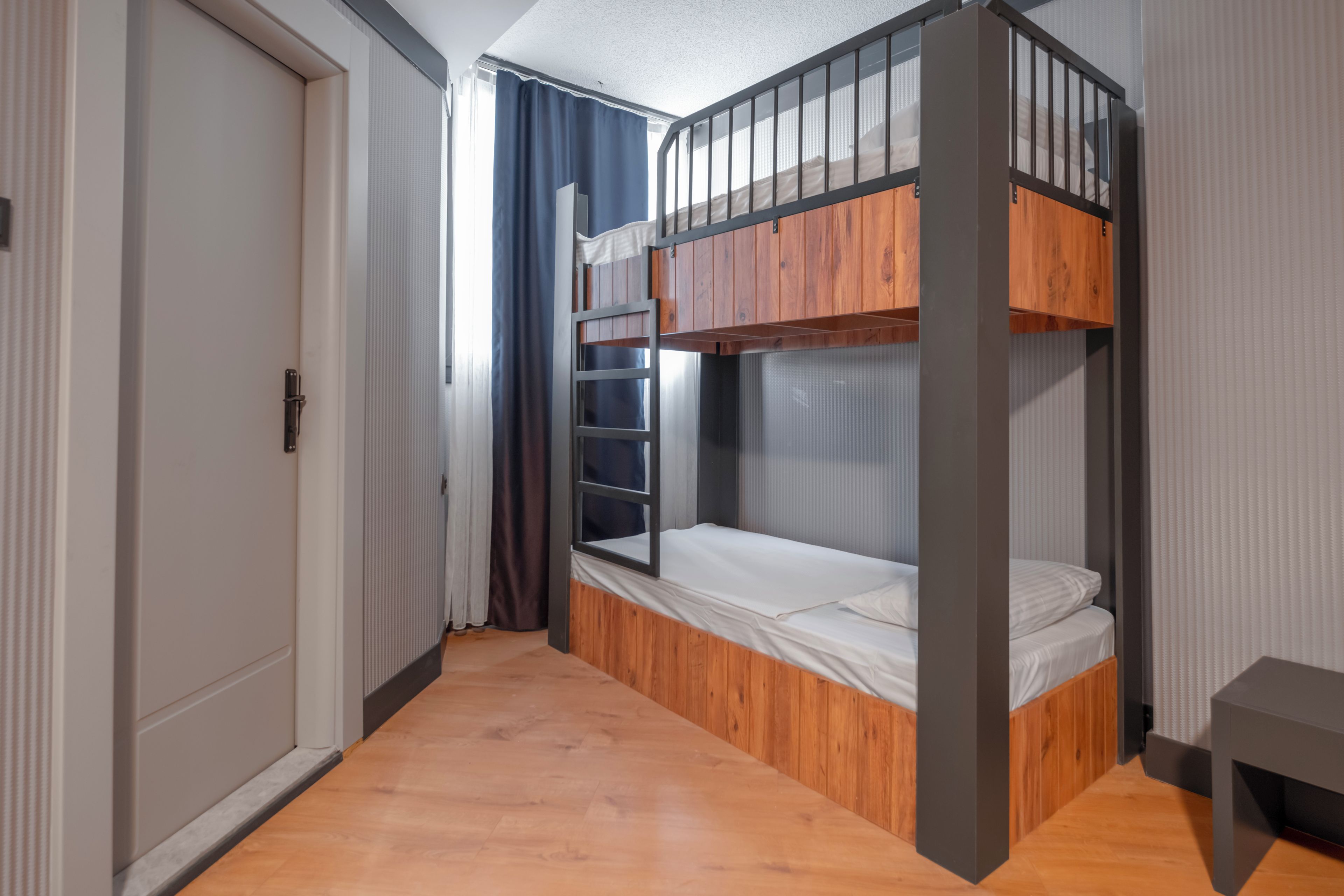 A room with a bunk bed, a door, and a small table.