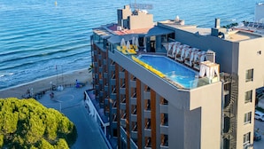 Un hotel con piscina infinita en la azotea, vistas a la playa y un diseño arquitectónico moderno.