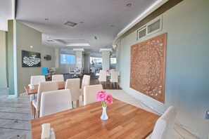 Un comedor moderno con una mesa de madera, sillas blancas y un jarrón con flores rosas.