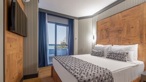 Habitación de hotel con una cama grande, televisión, balcón con vistas y paneles de madera.