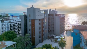 Un hotel moderno con varios pisos, un llamativo letrero de 'JURA HOTELS' y vista al mar.