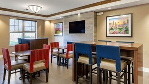 A restaurant with booths and high-top tables, a flat-screen TV mounted on the wall, and artwork on the walls. - Comfort Inn & Suites Cordele (Cordele)