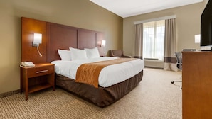A hotel room with a large bed, bedside tables, a desk, and a television. - Comfort Inn & Suites Cordele (Cordele)