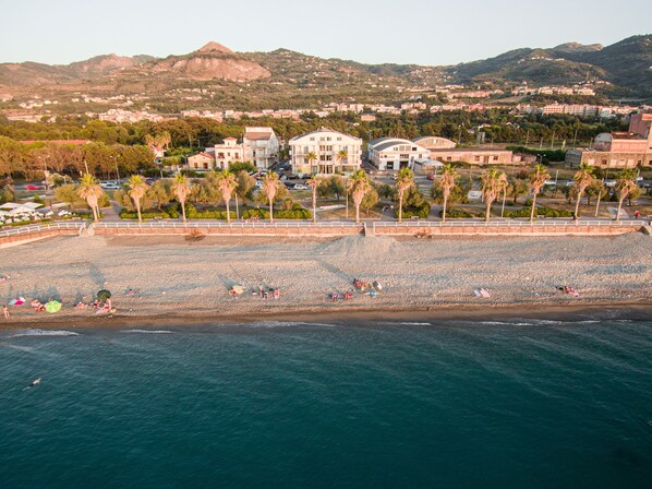Un pueblo costero con una playa, edificios y montañas al fondo.
