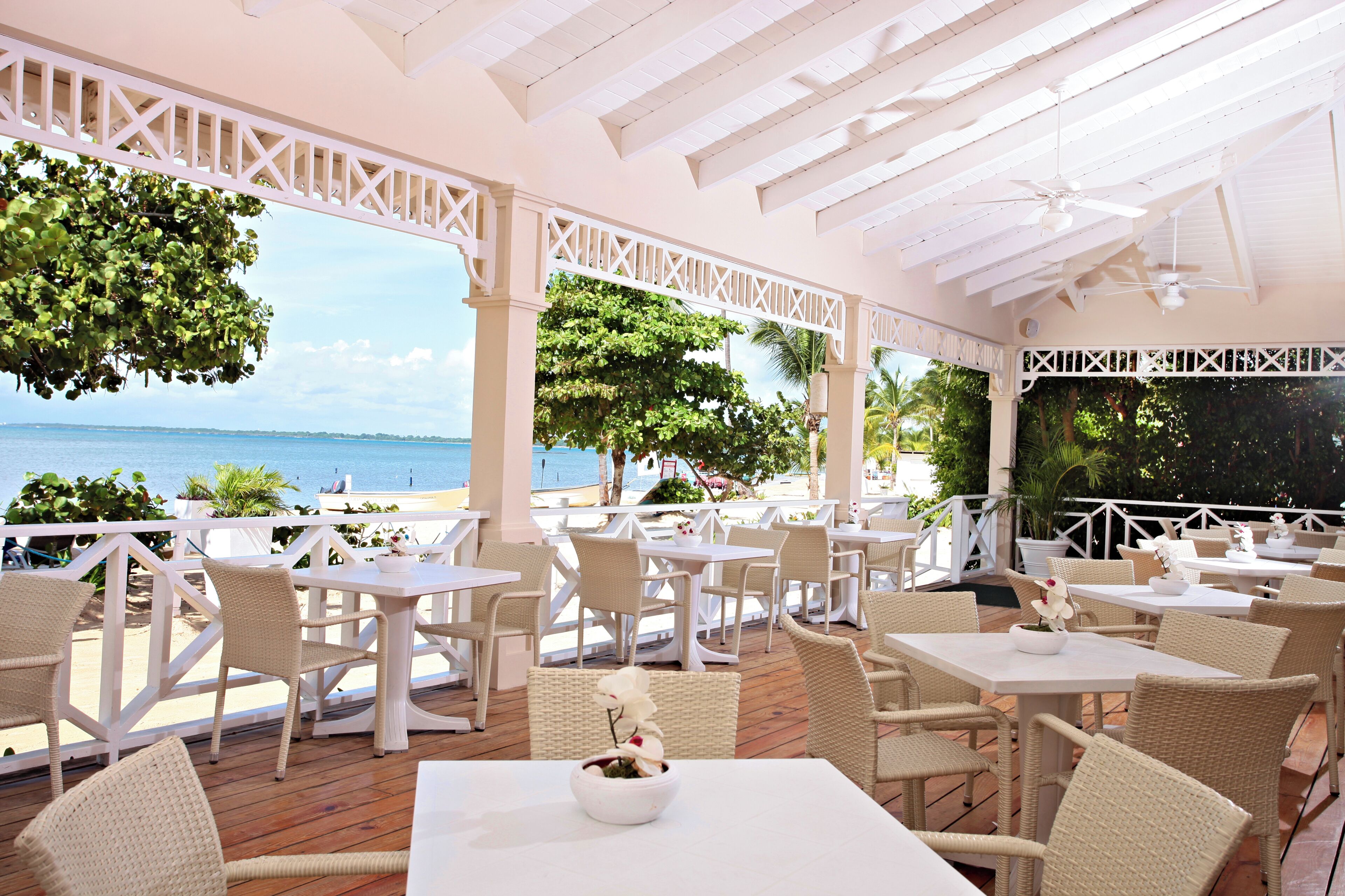 An outdoor patio with white furniture, a white ceiling, and a view of the sea.