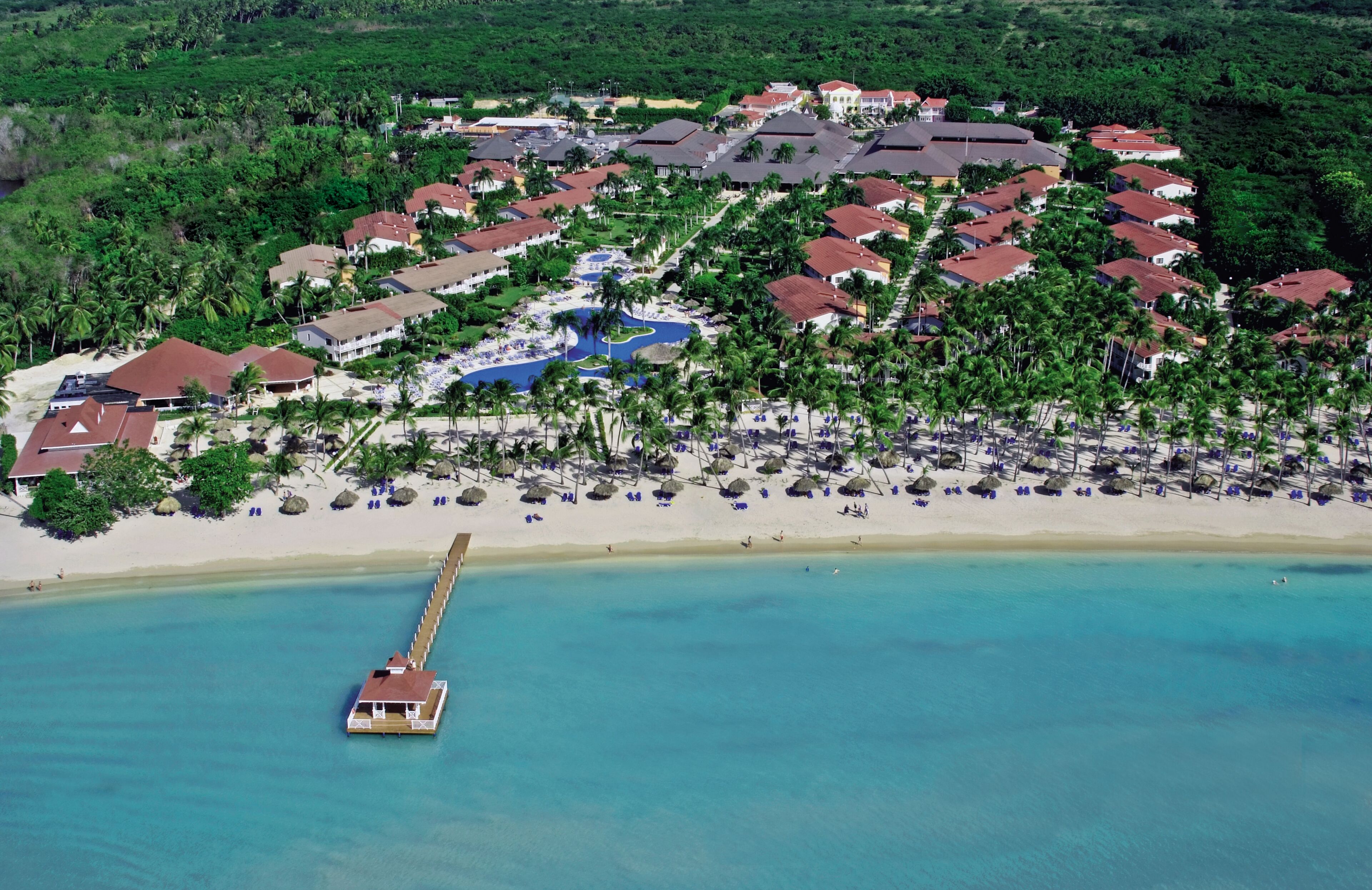 Vista aérea de um resort com vários edifícios, uma praia e um píer.