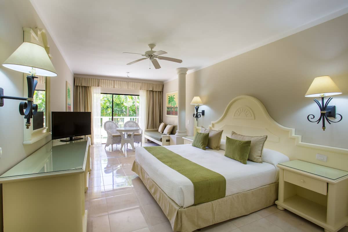 Une chambre d’hôtel avec un grand lit, une télévision, un ventilateur de plafond et une vue sur l’extérieur.