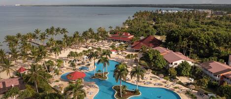 A resort with multiple swimming pools, palm trees, and beachfront views.