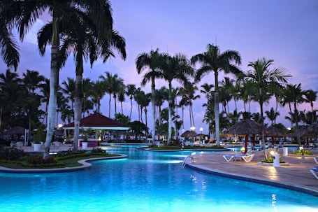 Una piscina al aire libre, sombrillas, sillones reclinables de piscina