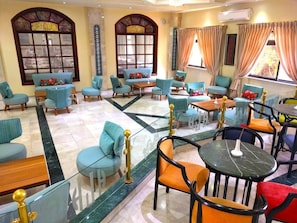 A hotel lobby with multiple seating areas, including sofas and chairs, arranged around a central coffee table.