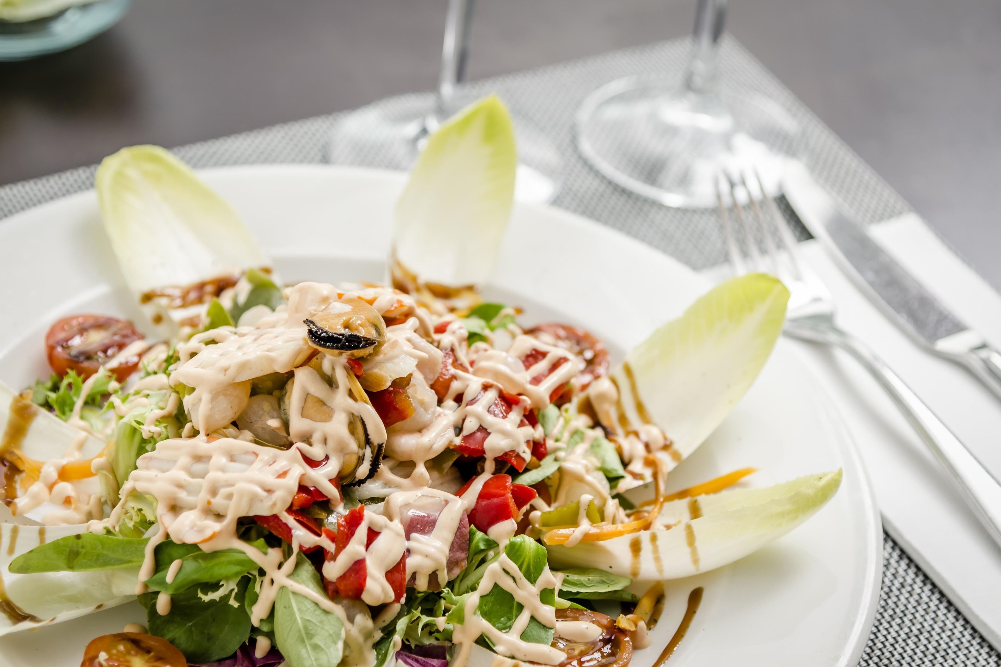 A plate of salad with various vegetables and a creamy dressing.
