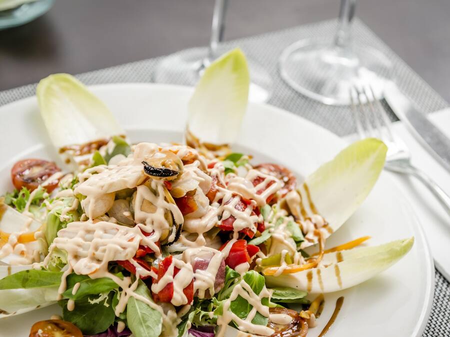 A plate of salad with various vegetables and a creamy dressing.