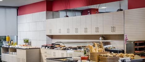 A modern kitchen with a buffet setup, featuring a variety of food items and a self-service station.