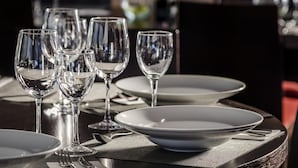 Une table dressée avec de la vaisselle en verre transparent et des assiettes blanches, ce qui évoque un cadre de repas formel.