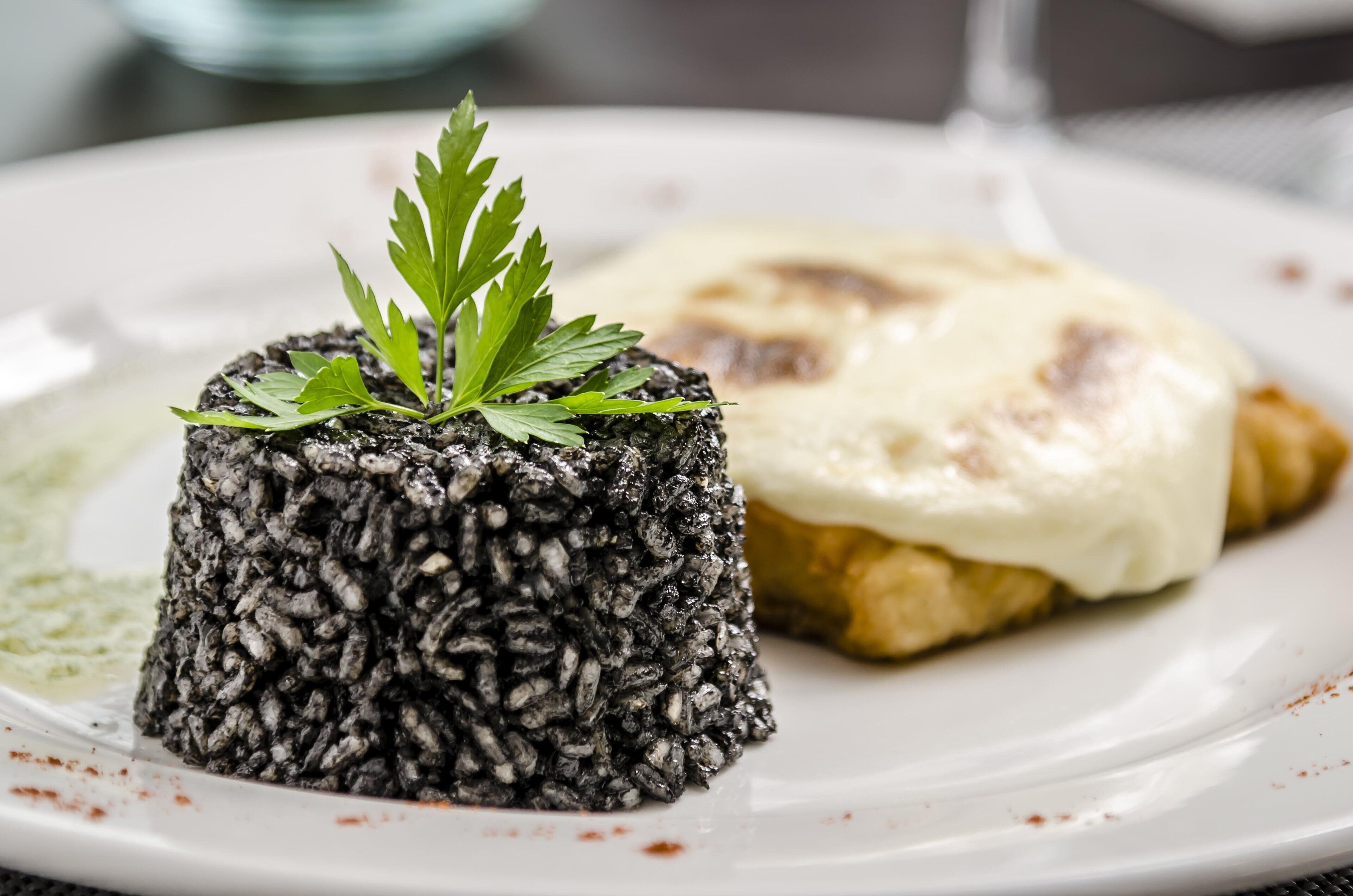Un piatto con tortino di riso nero e una fetta di pane con formaggio.