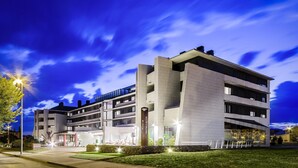 Un hôtel moderne à l’architecture imposante, doté d’un espace extérieur aménagé et d’une entrée bien éclairée.