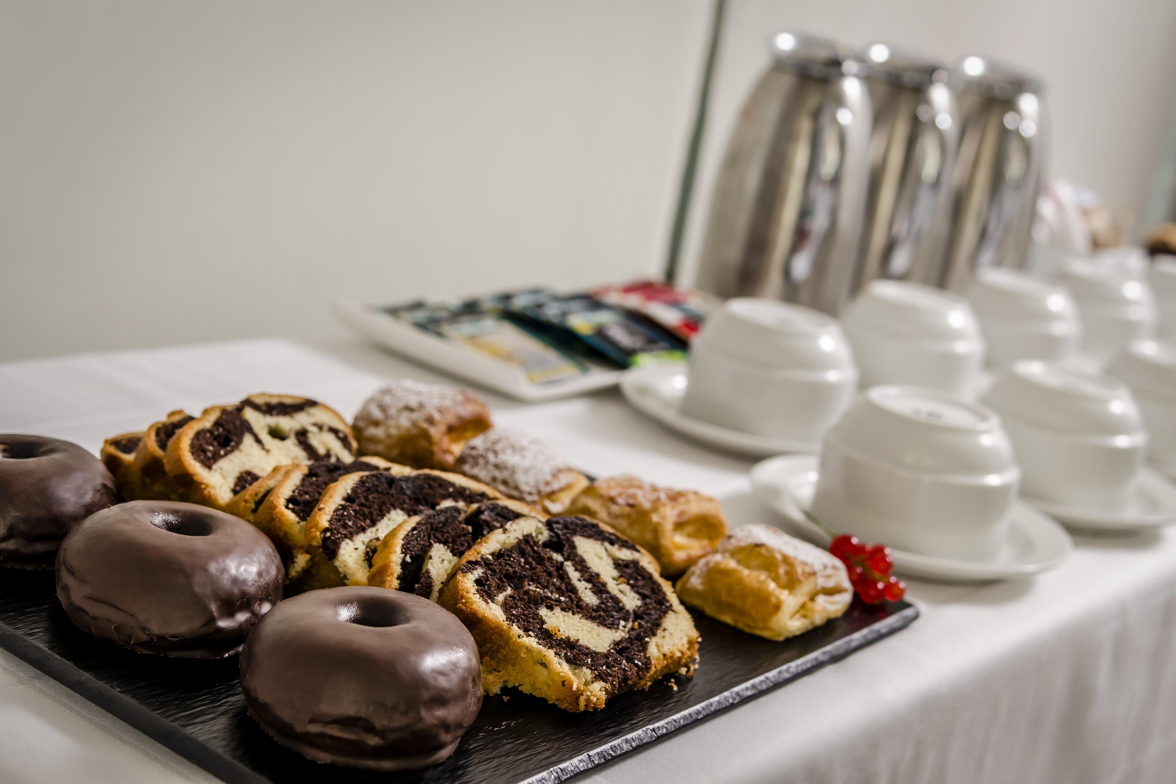 A table with pastries and coffee cups.