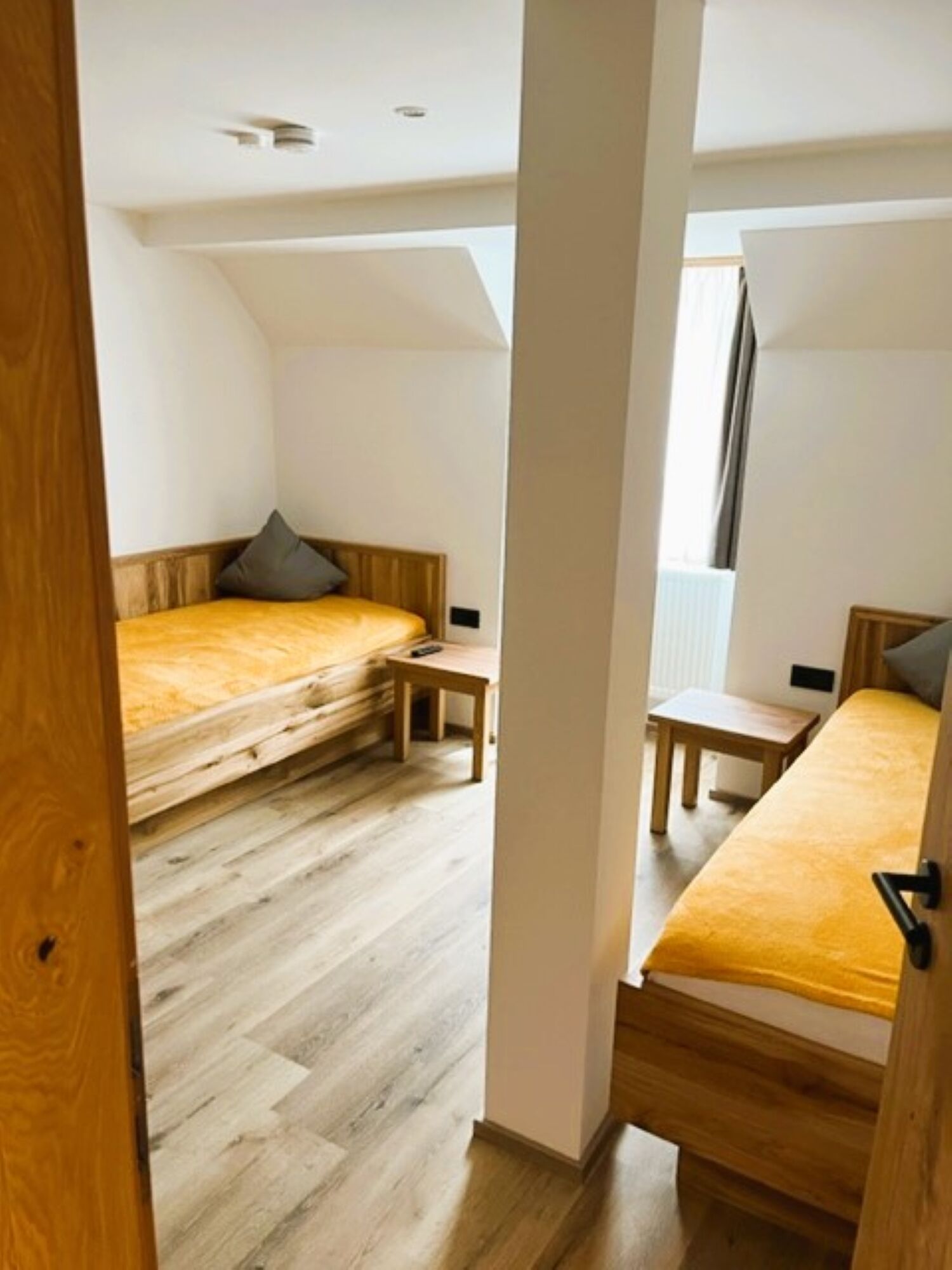 A compact, well-lit room with two beds, a small table, and a window.