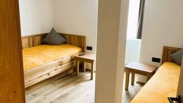 A compact, well-lit room with two beds, a small table, and a window.