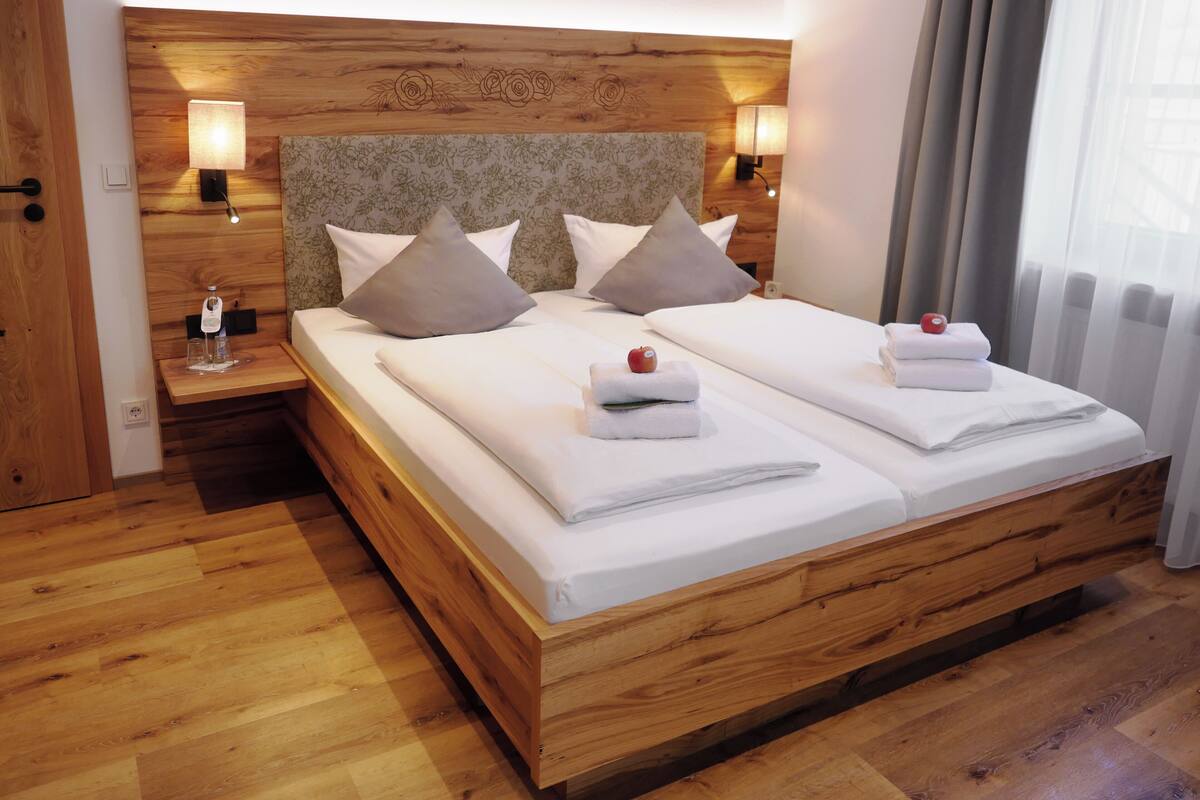 A double bed with a wooden headboard, two bedside tables with lamps, and a floral-patterned wall.