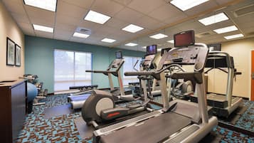 Un gimnasio con cintas de correr, elípticas y bicicletas estáticas.
